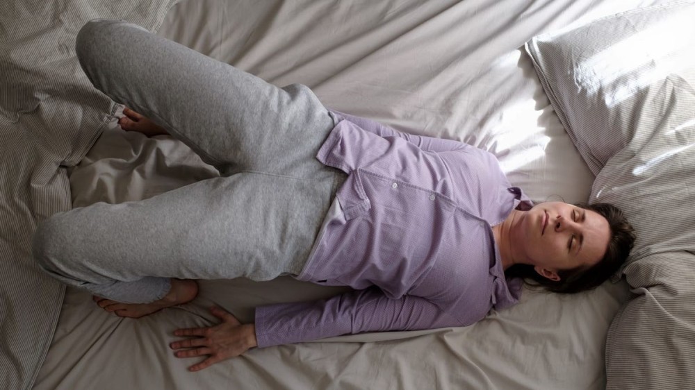 A woman doing bridge pose in bed.