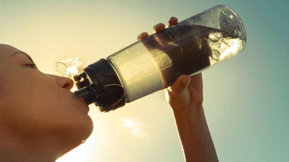 A woman taking a drink out of a water bottle. 