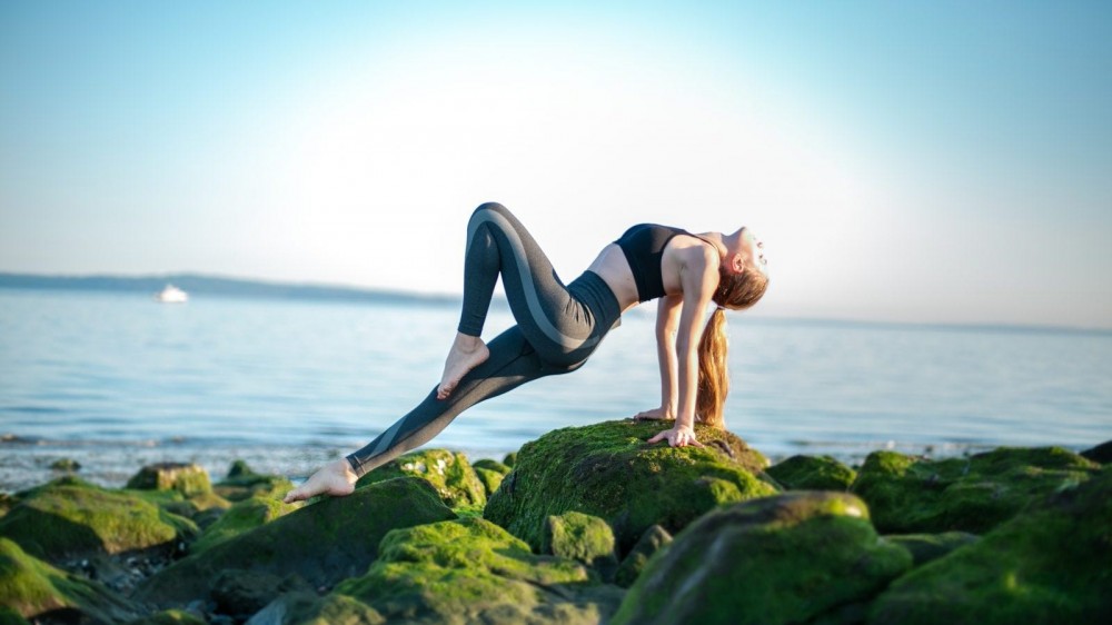 Woman doing an upward plank in front of a lake.